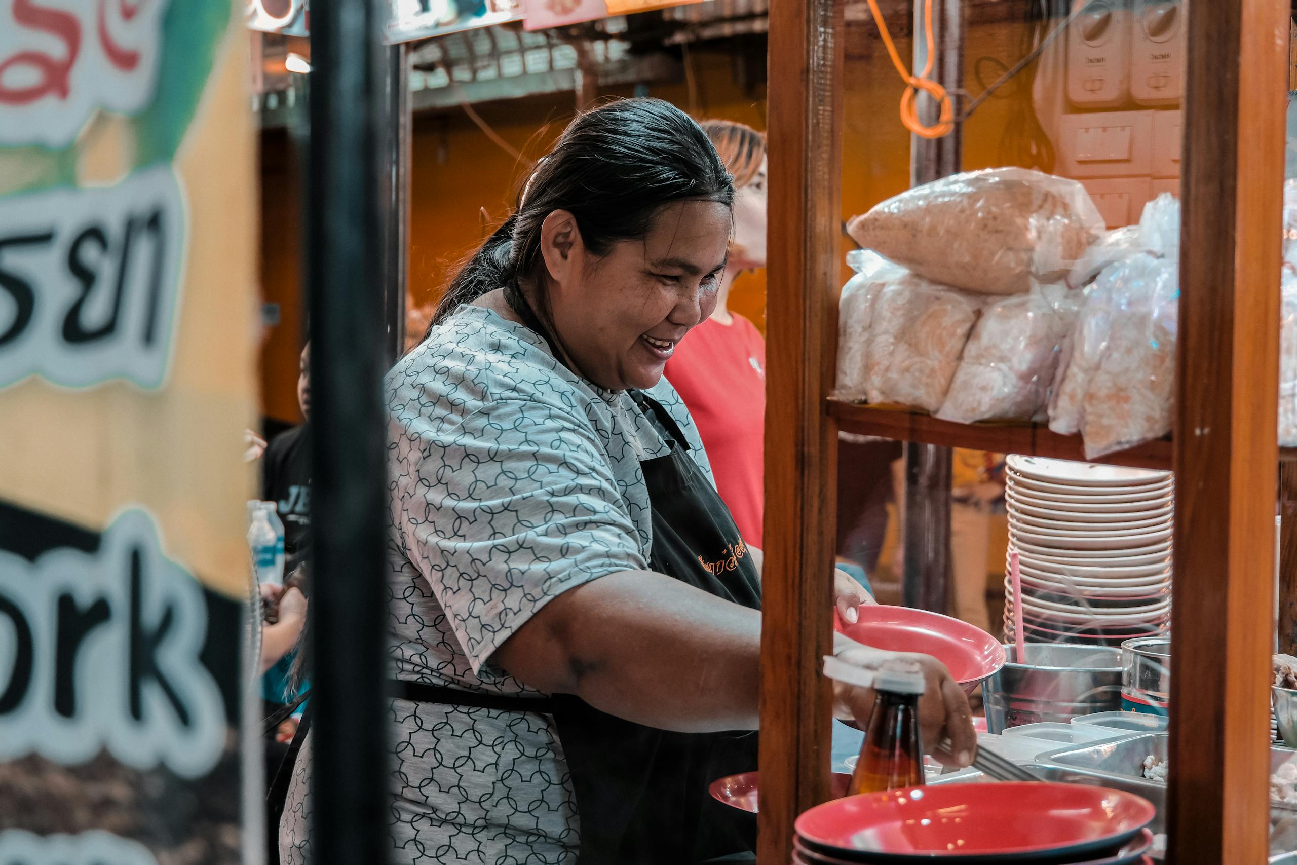 A cheerful vendor serving food at a vibrant Bangkok night market, showcasing Thai culture.